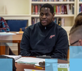 Male African American high school student sitting at a table in a library