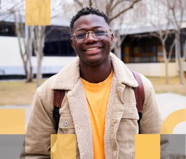 Estudiante de secundaria afroamericano sonriendo enfrente de una escuela secundaria