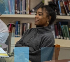 Estudiante afroamericana sentada en una mesa en una biblioteca